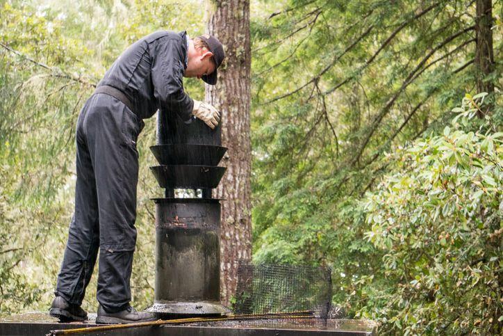 Mężczyzna montujący komin na tle lasu
